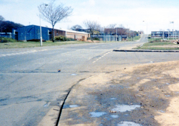 photograph of road flanked by industrial buildings rising in the distance