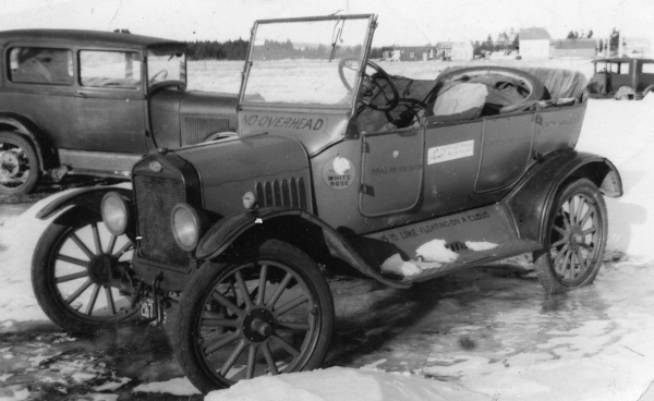 Old open-topped car in snow-covered yard