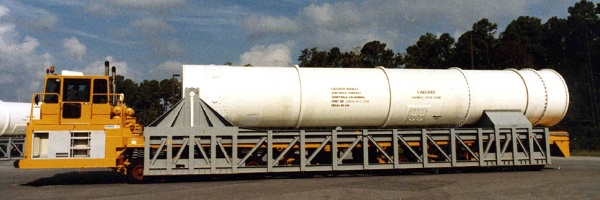 yellow lifting platform vehicle carrying a steel table cradling white missile loading tube