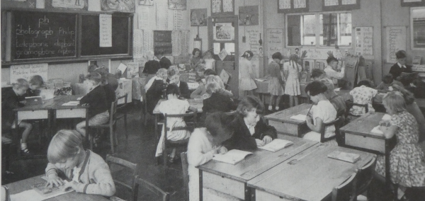 infants' school children sitting at desks reading