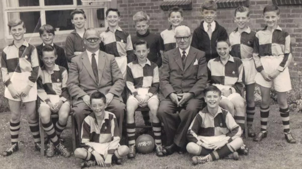 posed photo of boys' football team and two sittin men